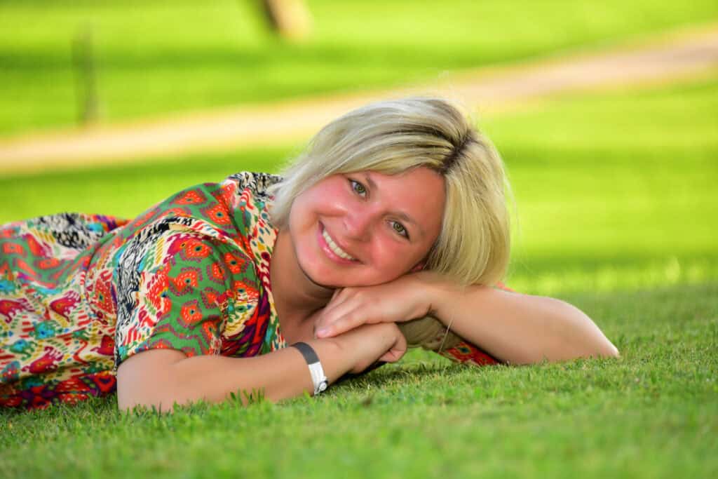 Jacqueline Kopf auf Händen abgelegt auf Wiese liegend