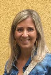 Frau mit blondem Haar, Jeansbluse vor gelber Wand
