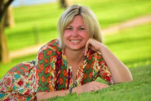 Porträt von Jacqueline Senner, liegend im Grünen, ruhig und lächelnd