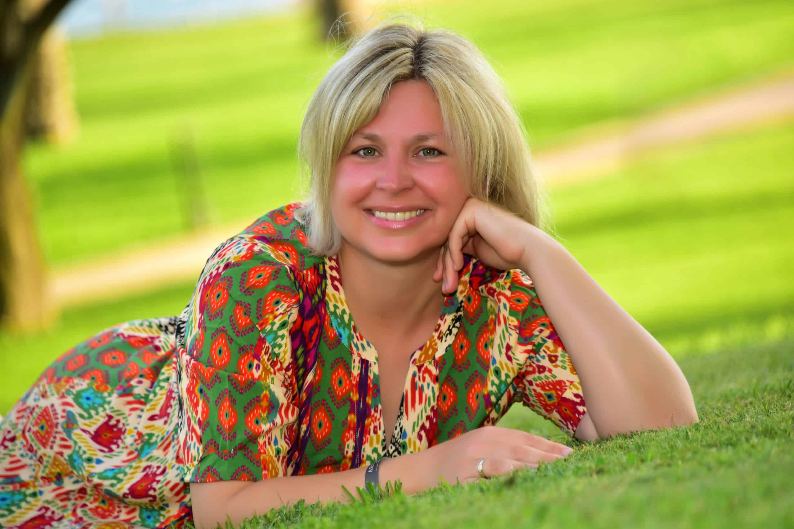 Porträt von Jacqueline Senner, liegend im Grünen, ruhig und lächelnd